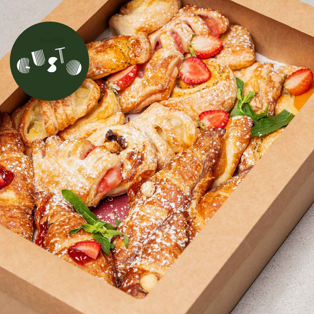 Pastry with strawberries and mint leaves in a box, branded 'Gusto'.