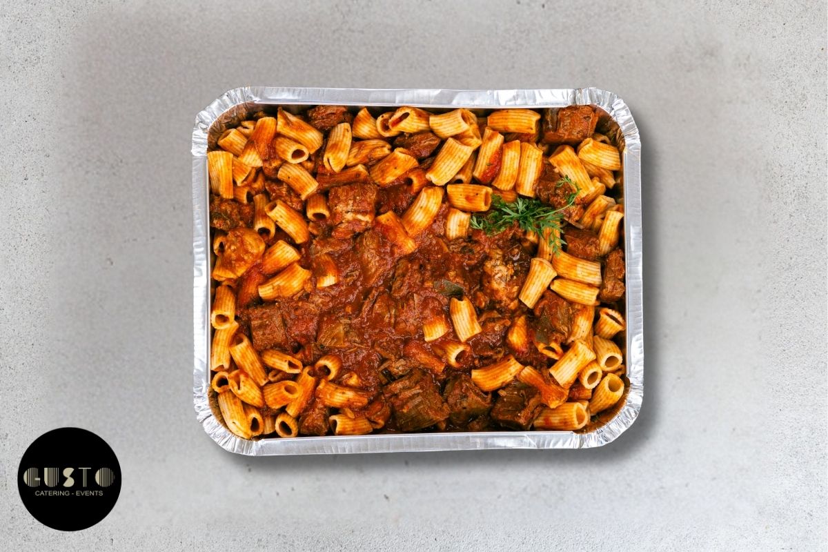 Aluminum tray of pasta with sauce on a gray background, featuring the Gusto logo.